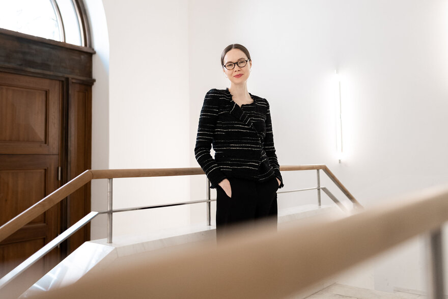 Elena Beregow standing in the foyer of the building where the College is located, entrance door in the background