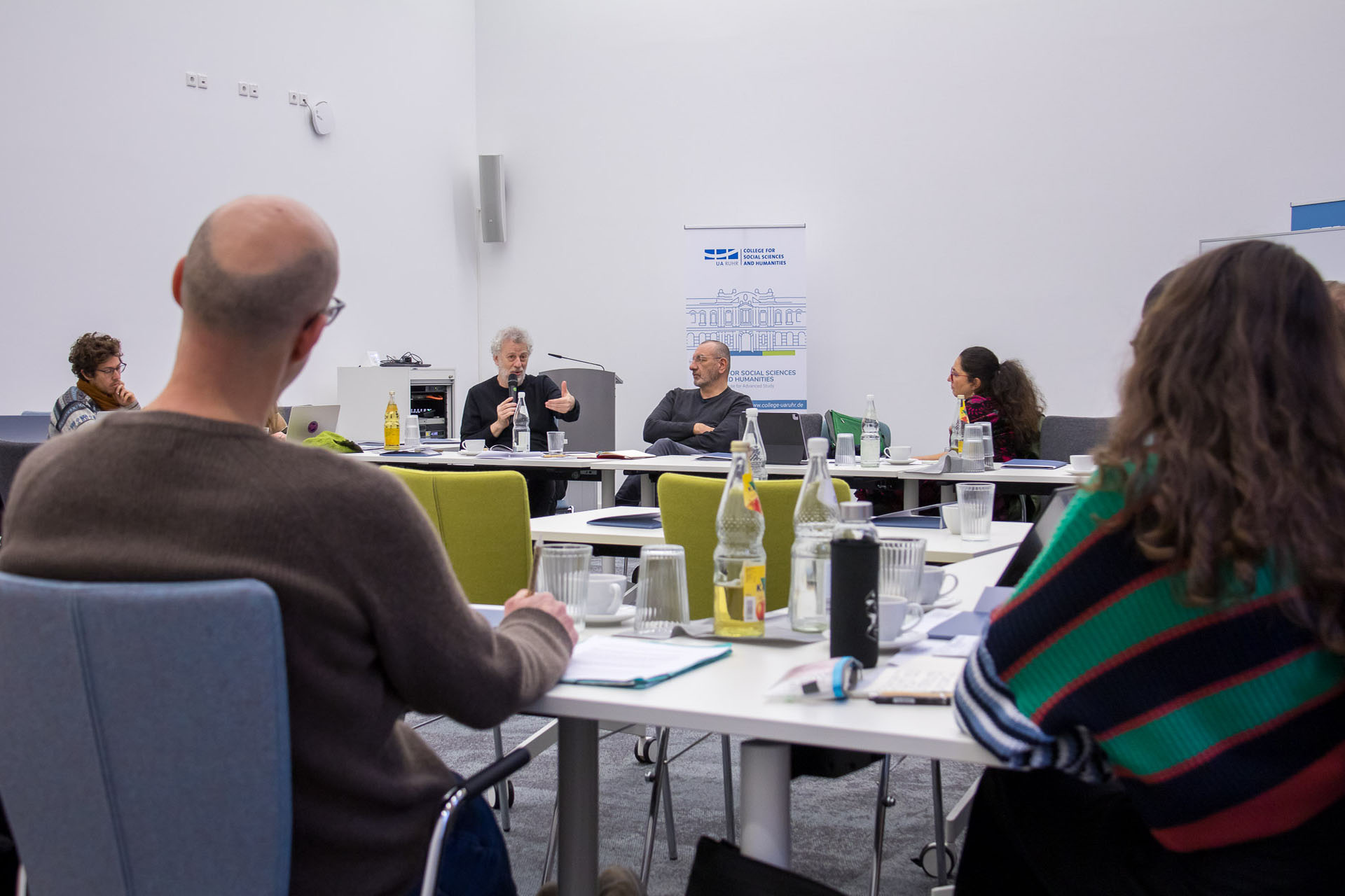 photo from the workshop, Prof. Feierstein speaking, participants sitting at tables