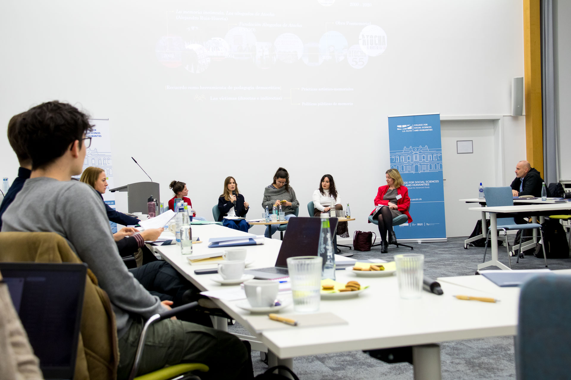 photo from the workshop 'Perpetrator Memory in Spanish culture', five panelists sitting in front of the audience, a screen with slides in the back