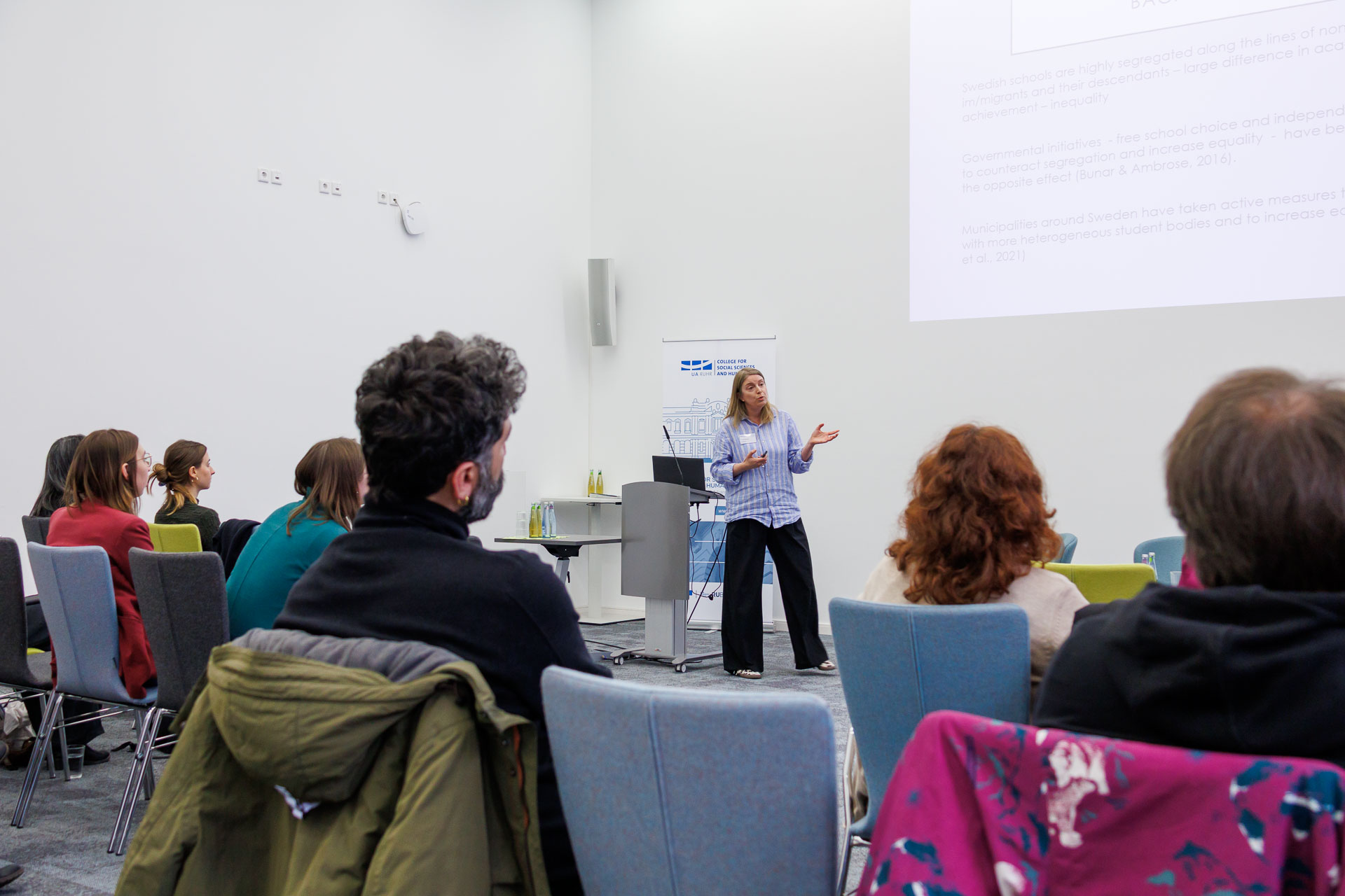 photo from the workshop 'Ethnic-Racial Socialisation', a speaker standing at the front, gesturing towards a projected slide